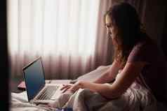 好早....社会媒体拍摄年轻的女人移动PC坐着床上
