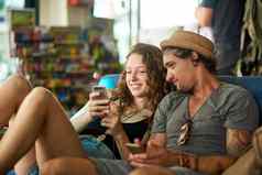 发布令人羡慕的假期图片拍摄年轻的旅游夫妇检查手机放松咖啡馆