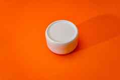 小白色塑料奶油Jar成员孤立的橙色背景