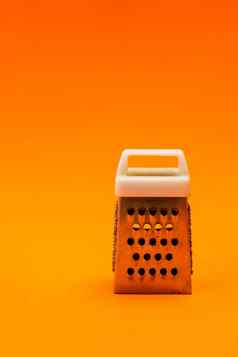 小闪亮的金属刨丝器孤立的橙色背景特写镜头奶酪食物不锈钢刨丝器垂直取向