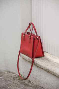 时尚珊瑚红色的crossbody袋白色混凝土背景crossbody袋使皮革