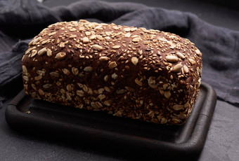 烤广场黑麦面粉面包燕麦片黑色的背景前视图