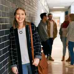 享受一年校园肖像年轻的女大学学生站校园走廊同学们背景
