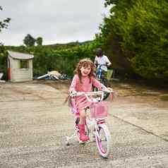 壳牌骑培训轮子肖像可爱的女孩骑自行车哥哥在户外