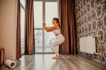 中间岁的运动有吸引力的女人练习瑜伽作品首页瑜伽工作室运动服装白色裤子全身的前在室内健康的生活方式概念