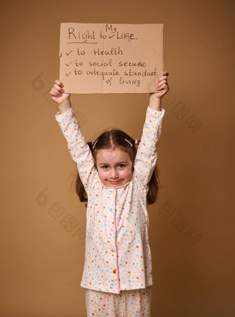 可爱的高加索人学前教育女孩持有纸板<strong>海报</strong>促进孩子们的权利足够的标准生活社会安全健康护理孤立的米色背景复制空间