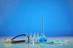 医疗瓶化学试剂灯泡透明的液体注射器面具扩音听诊器蓝色的背景冠状病毒流感大流行