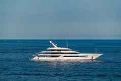巨大的大型游艇停泊海海岸天蓝色海岸线阳光明媚的一天铬镀扶手太阳反射光滑的董事会电动机船