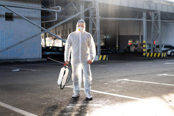 男人。穿着白色保护工作服喷涂表面抗菌洗手液喷雾器检疫
