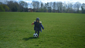 快乐家庭孩子们有趣的春天公园孩子运行孩子男孩运球黑色的白色经典足球球绿色草人玩足球童年体育运动冠军概念