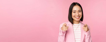 恭喜微笑热情的朝鲜文企业夫人女商人指出手指相机祝贺赞扬站粉红色的背景