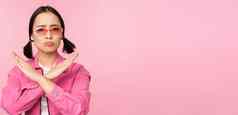肖像朝鲜文女孩时尚的太阳镜生闷气的失望显示停止拒绝手势交叉标志站粉红色的背景