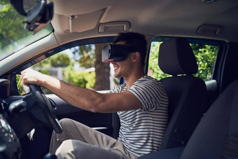 让技术测试开车拍摄快乐年轻的男人。开车车穿虚拟现实耳机