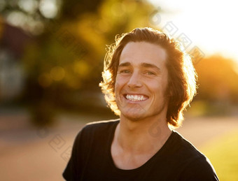夏季微笑肖像英俊的年轻的男人。站太阳