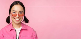 关闭时尚的朝鲜文女孩<strong>太阳镜</strong>微笑快乐摆姿势粉红色的背景人脸概念
