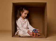 可爱的女孩睡衣坐着内部纸板盒子折小色彩斑斓的房子成矿磁建设块
