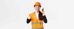 满意快乐微笑亚洲女工程师工业技术员安全头盔统一的显示竖起大拇指赞扬伟大的工作步话机给许可工作