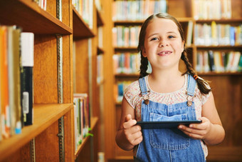 书肖像快乐的年轻的女孩浏览数字平板电脑站<strong>内部图书馆</strong>一天