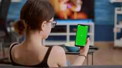 特写镜头年轻的女人持有垂直智能手机绿色屏幕在线会议集团视频调用