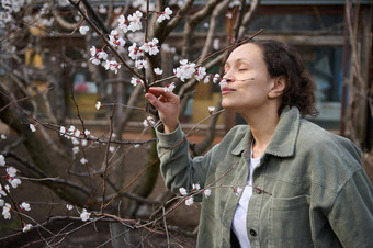 自信宁静拉美裔浅黑肤色的女人女人享受气味白色花分支开花杏水果树站花园<strong>情节</strong>早期春天一天