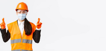 科维德安全协议企业建设防止病毒概念充满希望的亚洲女工程师头盔脸面具祈祷关闭眼睛交叉手指好运气白色背景