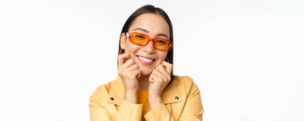 关闭肖像时尚的亚洲女人太阳镜触碰脸浪漫的微笑相机站白色背景