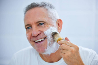今天护肤品一天拍摄成熟的男人。应用剃须奶油脸浴室首页