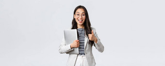 业务金融就业女成功的企业家概念年轻的自信女商人眼镜显示竖起大拇指手势持有移动PC保证服务质量