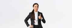很高兴女企业家夫人老板黑色的西装满意工作显示竖起大拇指点头批准赞美伟大的工作站白色背景