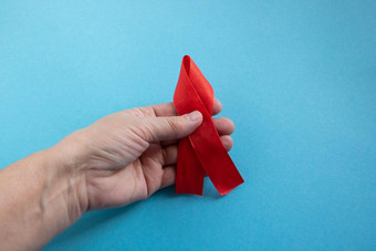 手持有红色的丝带蓝色的背景概念世界艾滋病一天捐赠一天血友病一天
