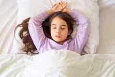 浅黑肤色的女人女孩长头发紫色的睡衣睡觉手白色枕头