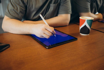 年轻的有<strong>创意</strong>的网络设计师便装咖啡饼干画手写笔平板电脑工作