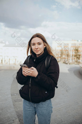 华丽的美丽的年轻的女人金发女郎头发消息传递智能手机城市街背景