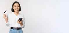 在线购物概念图像年轻的亚洲现代女人持有信贷卡智能手机购买智能手机应用程序支付非接触式站白色背景