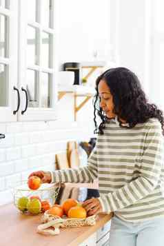 微笑非裔美国人女选择健康的零食排序苹果厨房