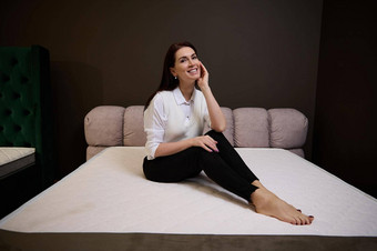 高加索人漂亮的女人坐着整形床垫家具商店