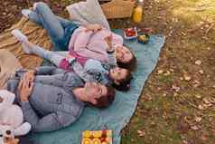 采取家庭时间公园拍摄快乐年轻的家庭享受野餐公园