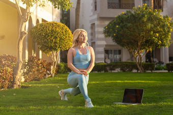 女孩实践瑜伽户外健康的生活方式女人穿运动服装院子里度假胜地酒店