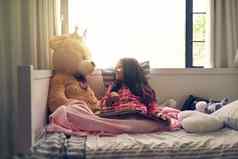 显示图片拍摄可爱的女孩阅读书泰迪熊床上