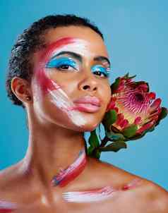色彩鲜艳的花工作室肖像美丽的年轻的女人覆盖脸油漆摆姿势蓝色的背景