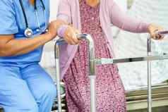 照顾者亚洲上了年纪的女人残疾病人走沃克护理医院医疗概念