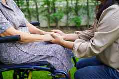照顾者亚洲上了年纪的女人残疾病人坐着轮椅公园医疗概念
