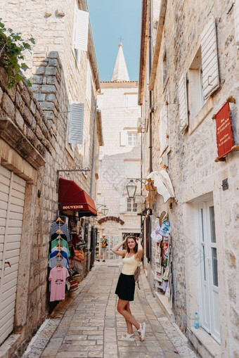女孩旅游走古老的狭窄的街美丽的夏天一天地中海中世纪的城市小镇布德瓦黑山共和国年轻的美丽的快乐的女人走街热带小镇漂亮的女孩微笑