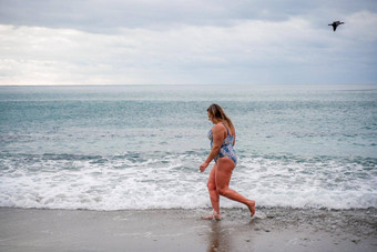 丰满女人洗澡西装进入水冲浪海滩灰色的天空<strong>云游</strong>泳冬天