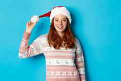冬天圣诞节夏娃概念可爱的红色头发的人女孩圣诞老人他微笑相机站毛衣蓝色的backgroudn