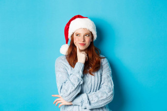 冬天假期圣诞节夏娃概念愚蠢的红色头发的人女孩雀斑穿圣诞老人他思考<strong>规划</strong>一年庆祝<strong>活动</strong>站蓝色的背景