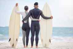 生病了骑波拍摄年轻的夫妇持有冲浪板海滩