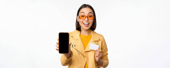 在线购物人概念时尚的亚洲女人显示移动电话屏幕信贷卡智能<strong>手机</strong>应用程序站白色背景