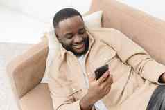 黑色的的家伙智能手机浏览互联网发短信说谎沙发首页网络社会媒体应用程序移动连接