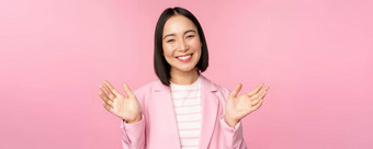 肖像微笑亚洲办公室夫人女商人提高手挥舞着快乐摆姿势西装粉红色的背景